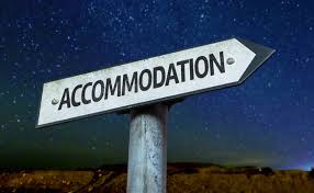 This image is of a direction sign with the word " Accommodation" mentioned on it. There is a night sky with stars in the background.