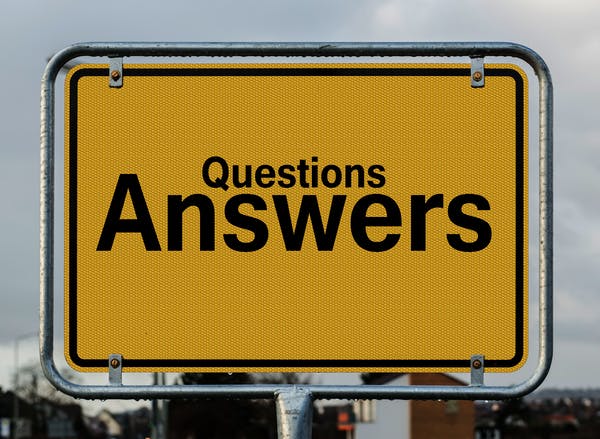 This is a rectangular metal board with writing " Questions Answers" on a yellow background.