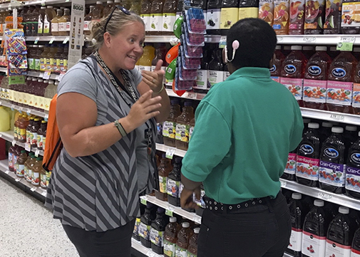 This image is from a grocery store. It appears that a woman seems to be talking in sign language with a male staff in the store. The staff looks like are wearing a hearing aid.