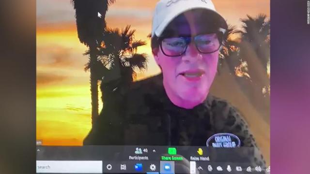 This is a screenshot of a video call, where the person on the screen is wearing a cap and eyeglasses. The background appears to be a sunset evening and trees.