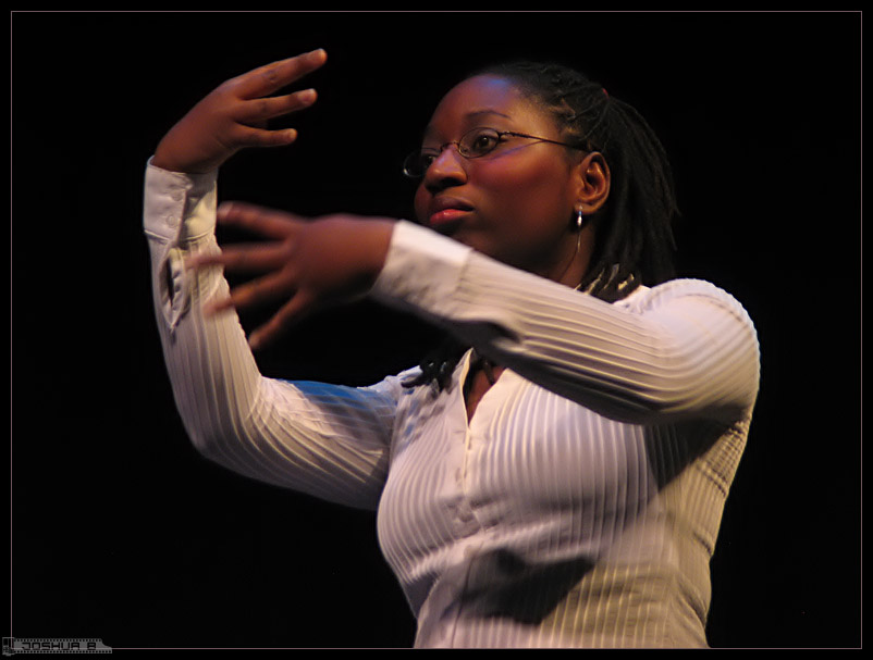 This image shows a woman using sign language to interact. She appears to be on a stage and interacting with the audience.