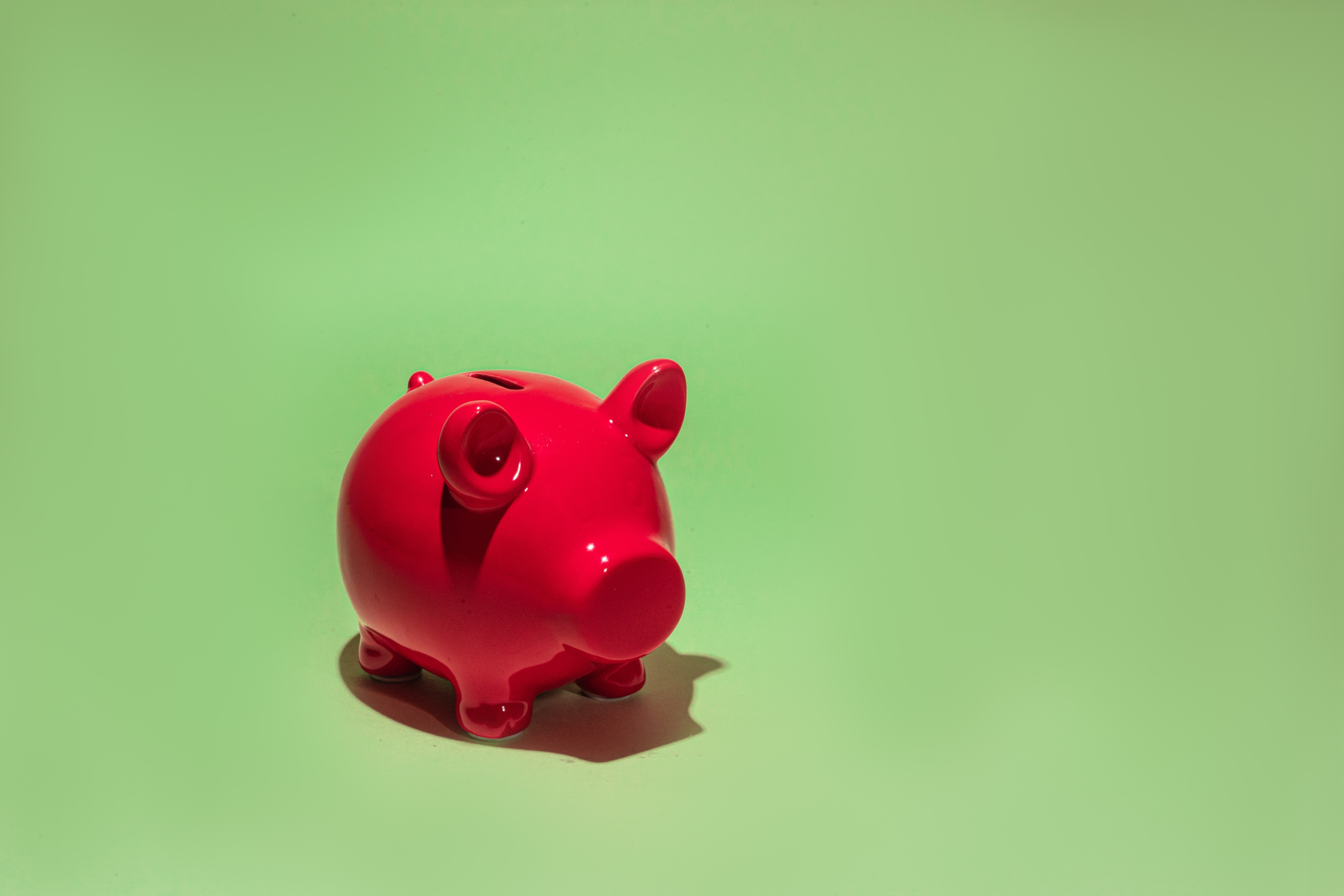 This image is of a Red piggy bank, and the background of the image is green.