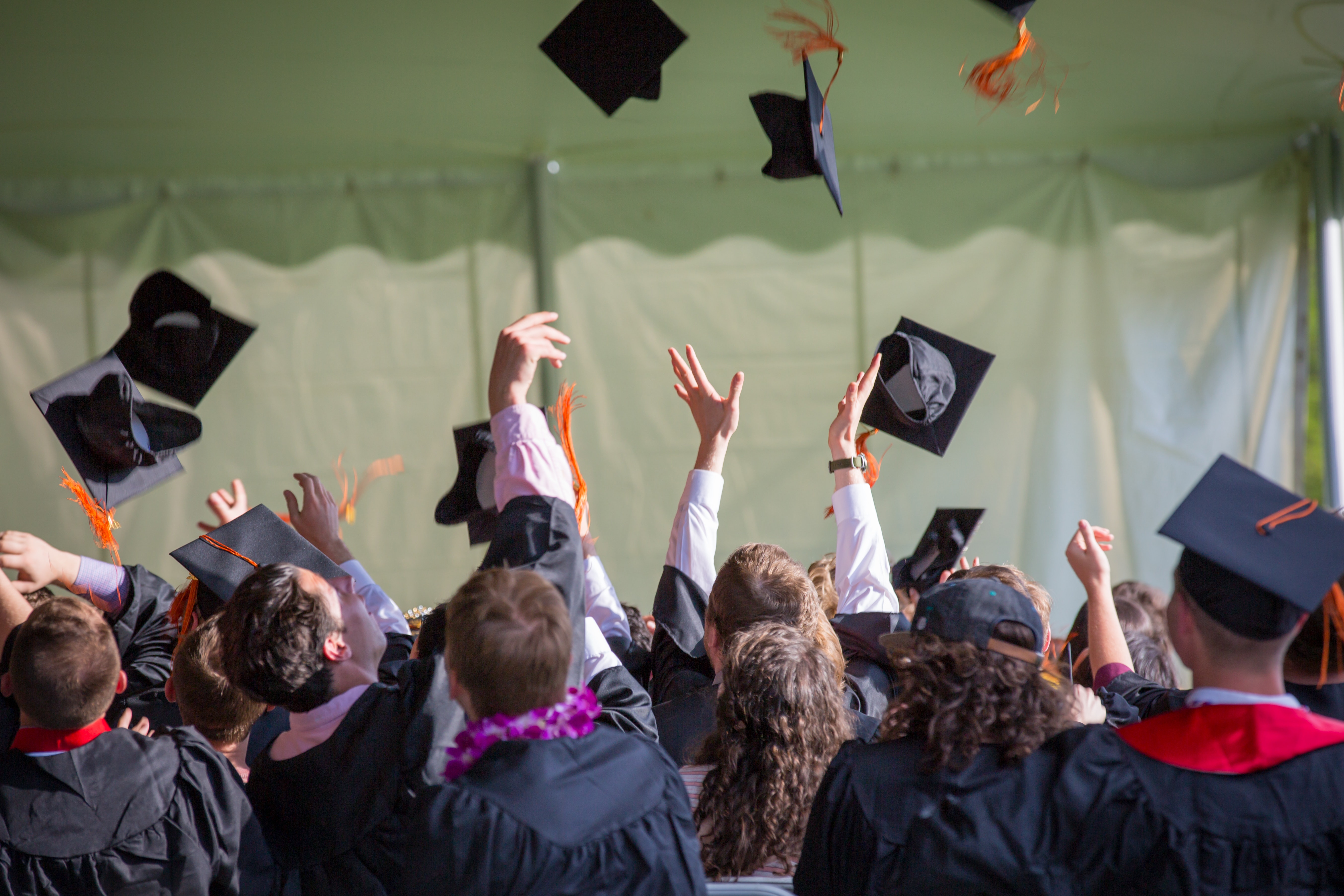 This image is from a graduation ceremony, where kids are throwing their graduation hats in the air. All the students wore black gowns.