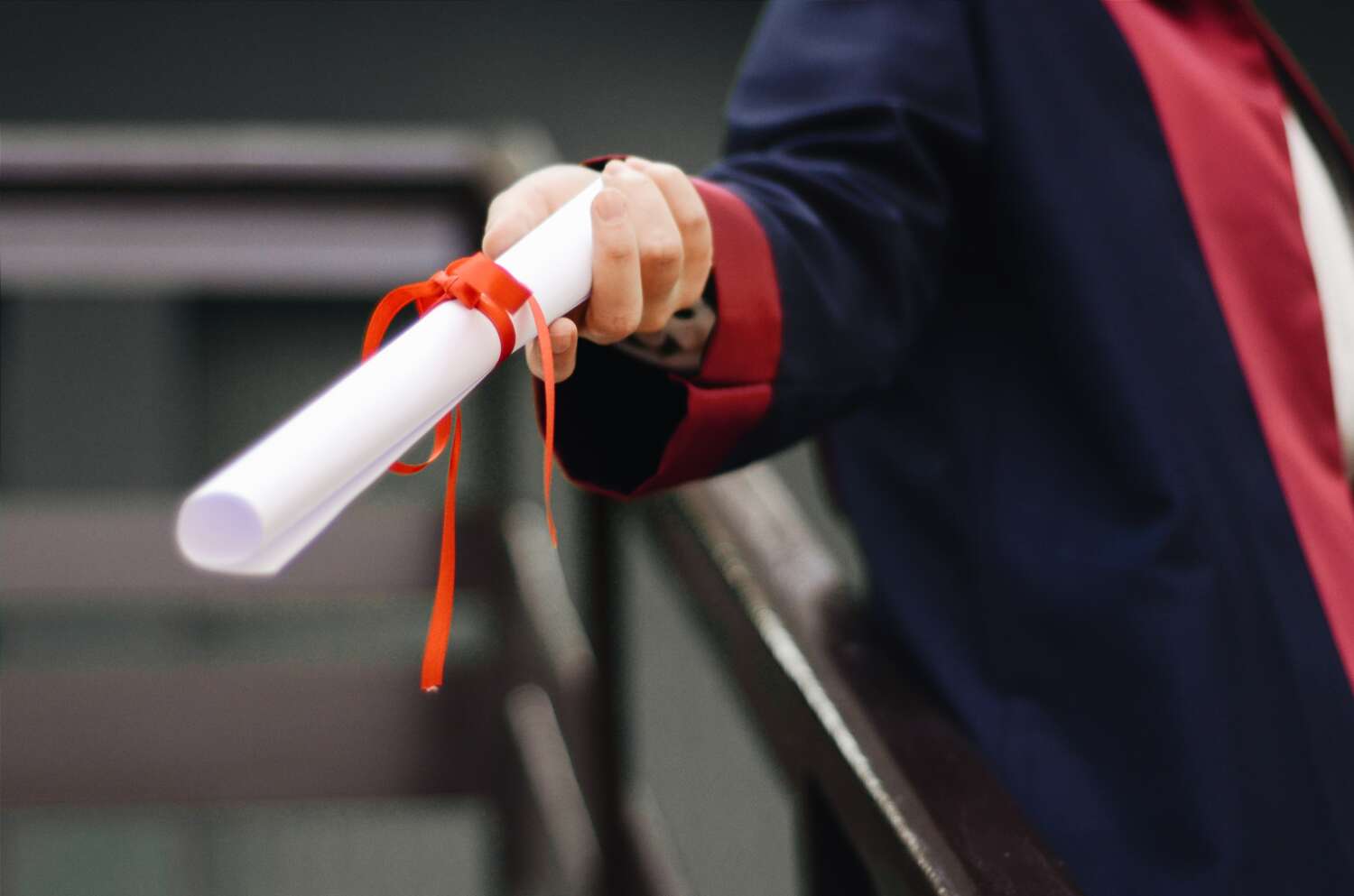 This image shows a person in a graduation gown holding the diploma in their hands.