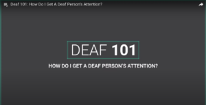 A video screenshot with the text "DEAF 101" and "HOW DO I GET A DEAF PERSON'S ATTENTION?."