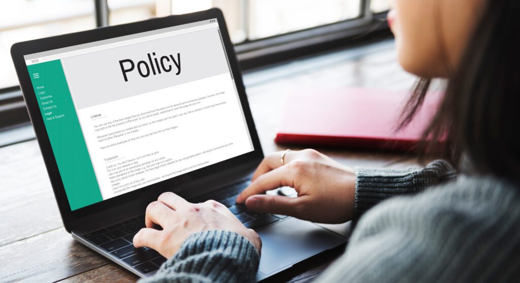 A person using laptop indoors looking at a document related to policy.