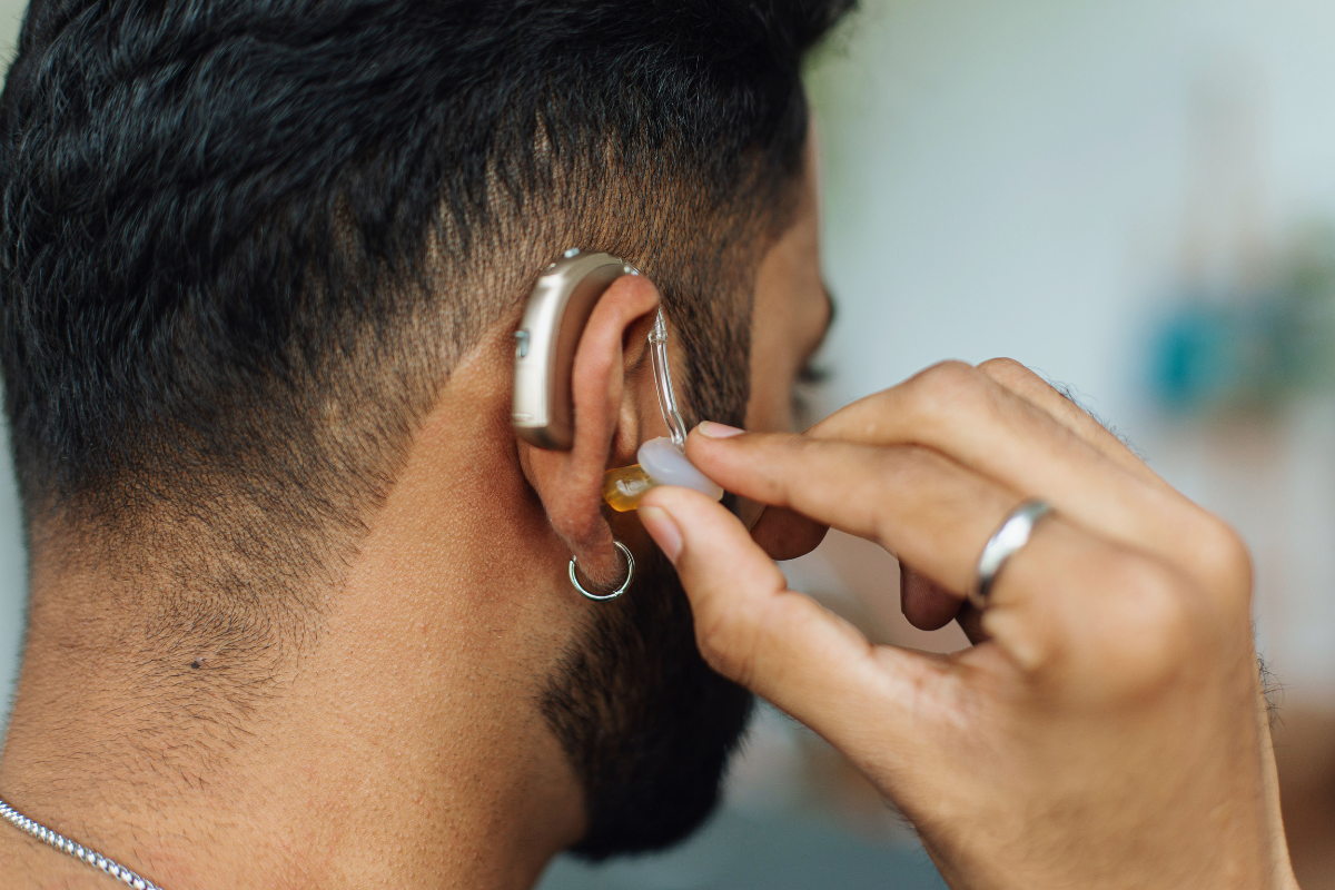 A back side picture of a person putting on a hearing aid.