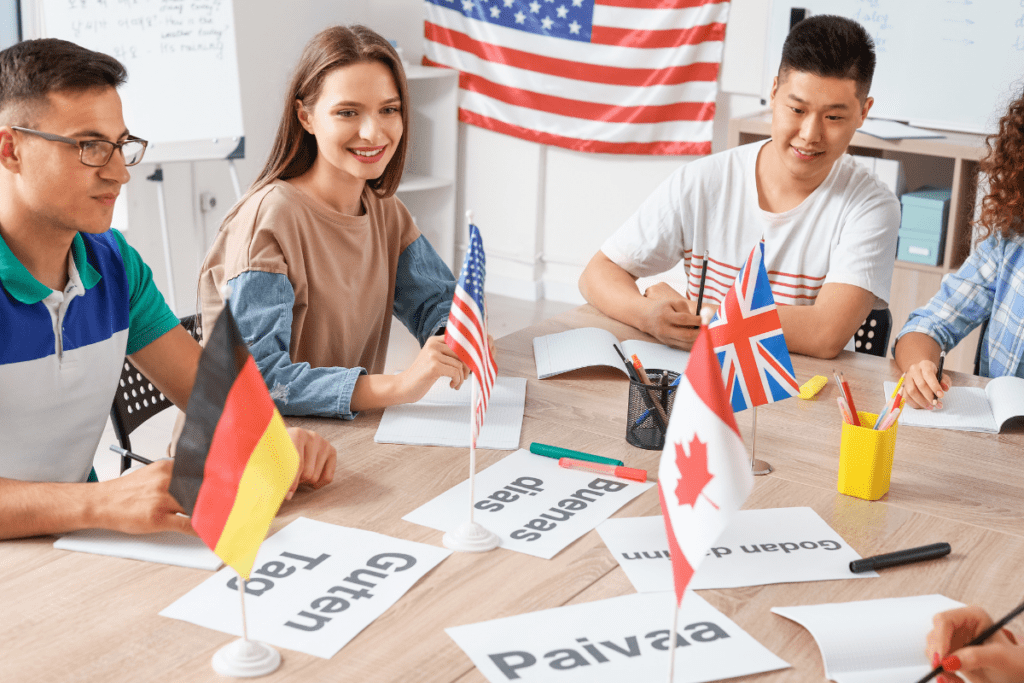 Three people are sitting at a table with flags from different countries. They seem to be engaged in a conversation about the flags.