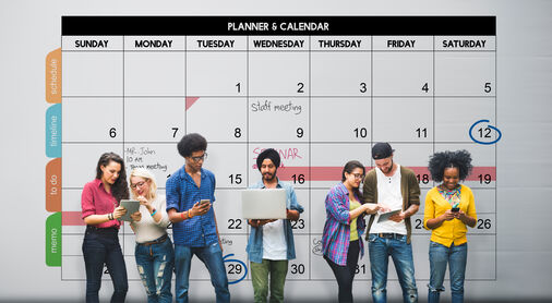 Group of diverse people in colorful clothes checking planners with a calendar in background.