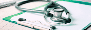 A stethoscope atop a clipboard on a table.
