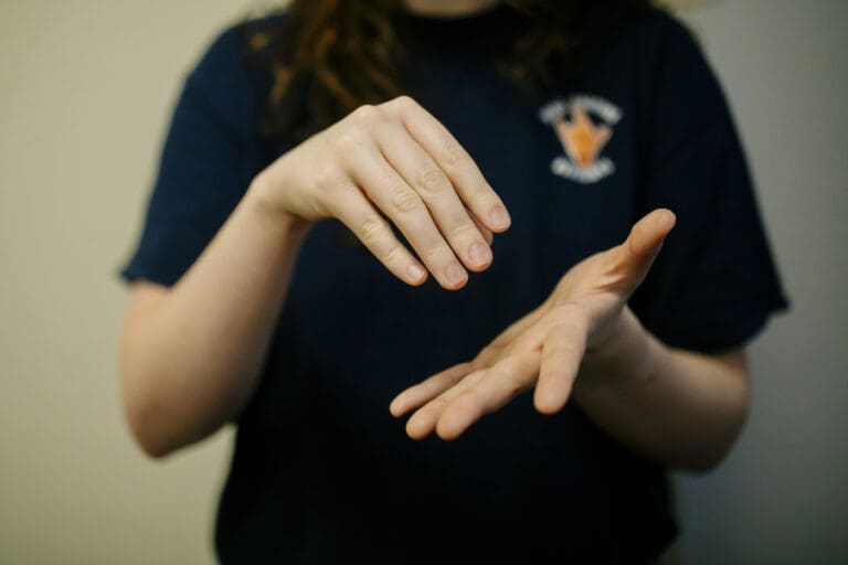 Person demonstrating American Sign Language with both hands signing "Student"